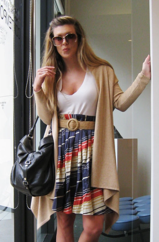 a woman in a dress and cardigan is walking by the door