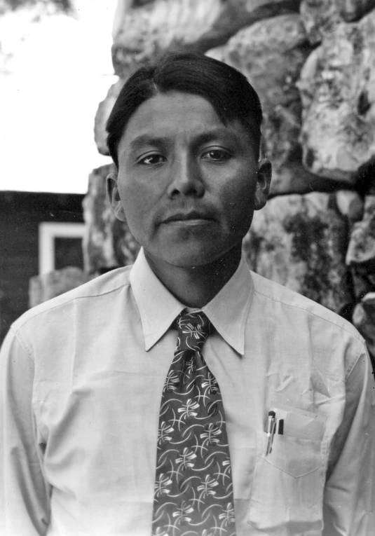 a man in a tie stands by a rock