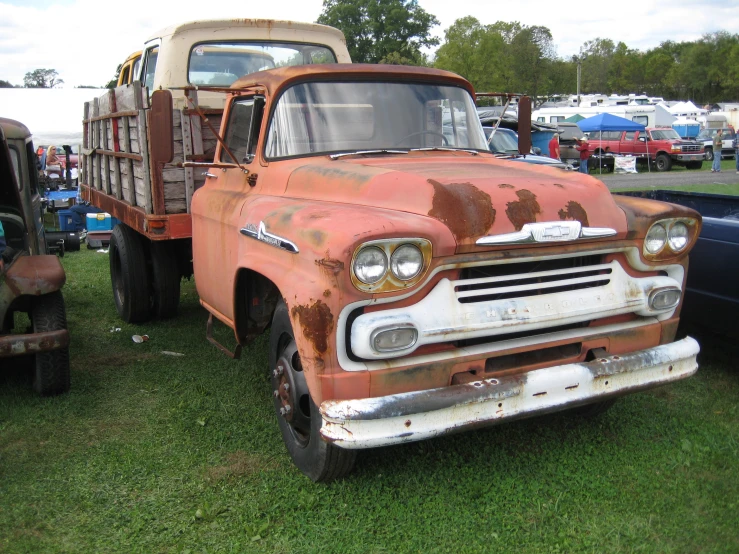 an old, rusted pickup truck is parked in the grass