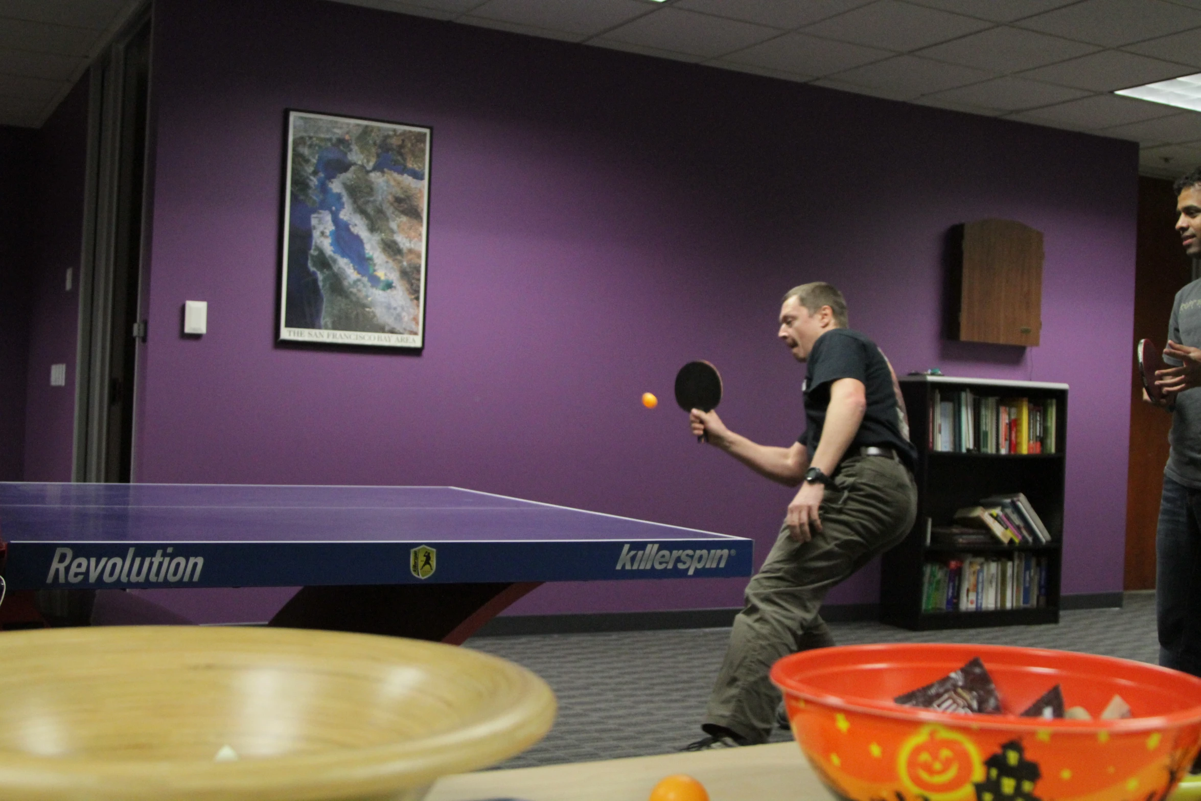 two guys playing table tennis in an office