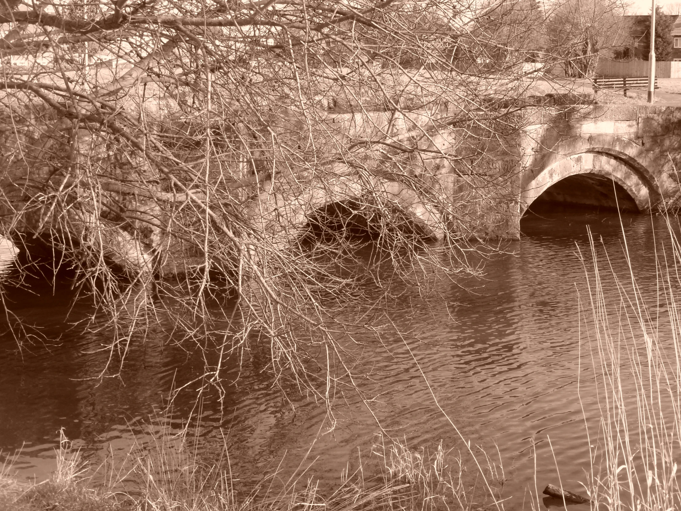 a waterway runs through an old, concrete city bridge