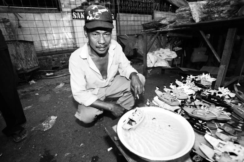 the man crouches beside a white plate filled with food