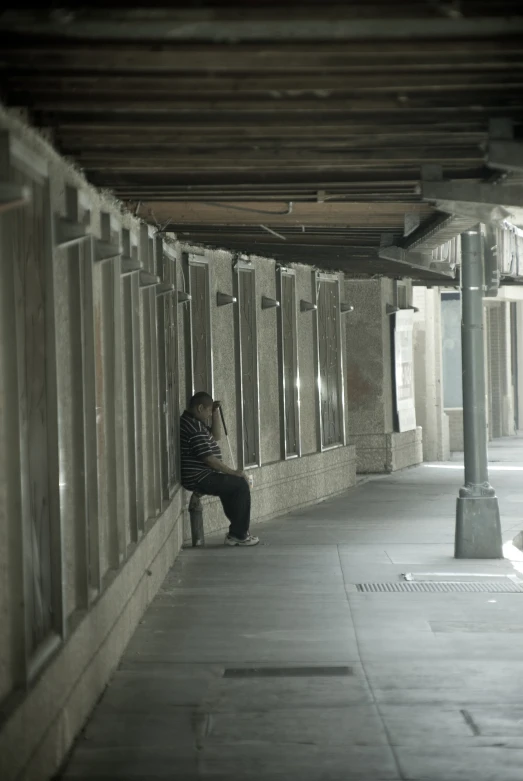 man sitting alone on bench in large tunnel