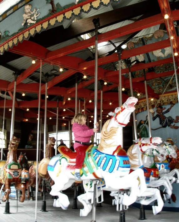 a woman standing on a carousel in front of some white horses