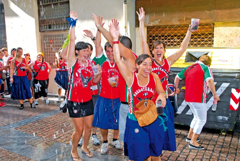 group of people with their arms in the air and two of them holding up a phone