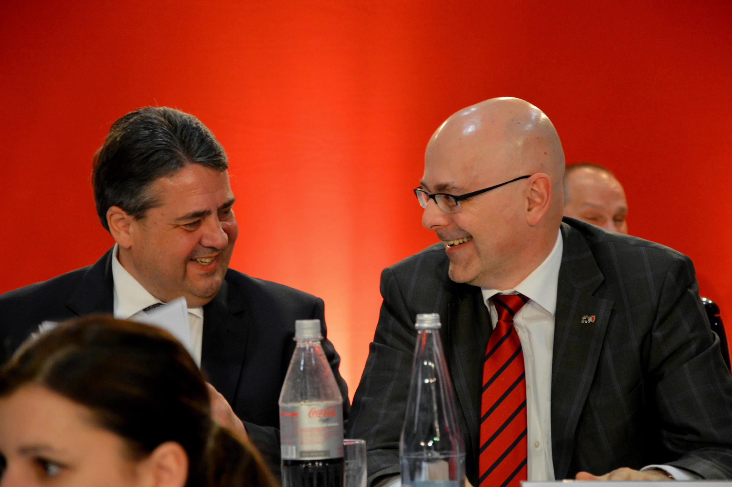 two men laughing and sitting at a table