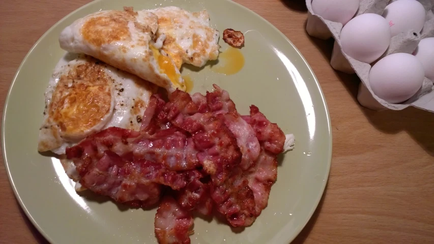 a green plate filled with eggs and bacon