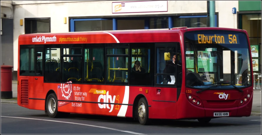 a bus driving down the road past a tall building