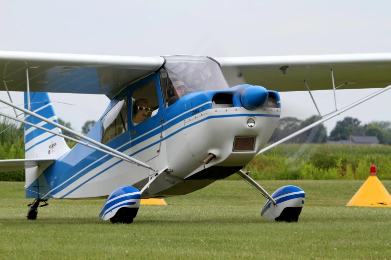 a blue and white plane with one pilot on the wing