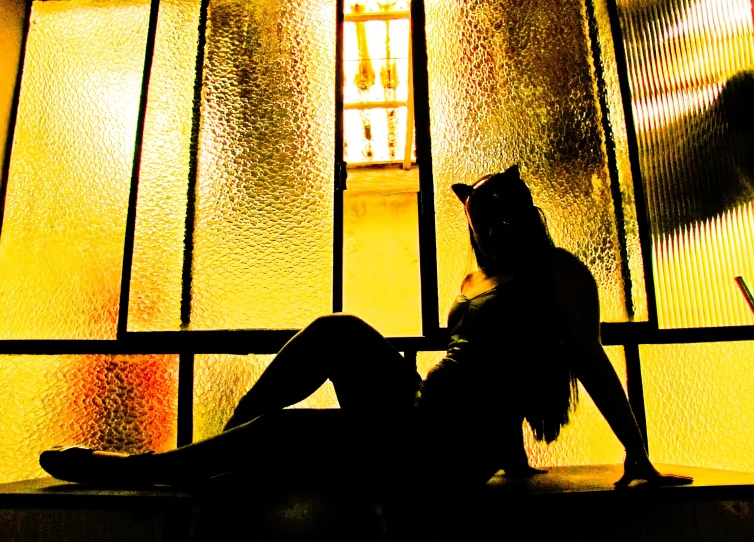 a silhouette of a person sitting next to a window