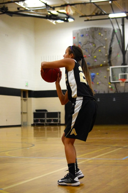 a girl is holding a basketball while a guy stands behind her and watches her