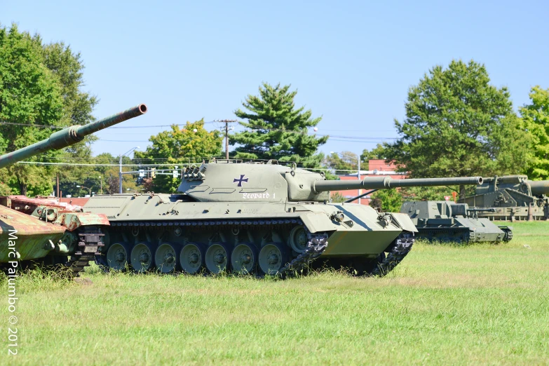 two large army tanks sit parked next to each other on the grass