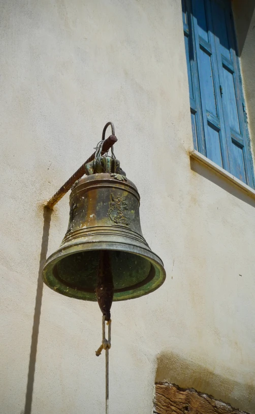 the old bell is hanging outside on the wall