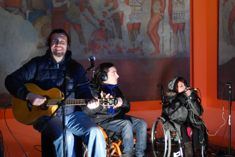 two people playing guitars in front of wall paintings