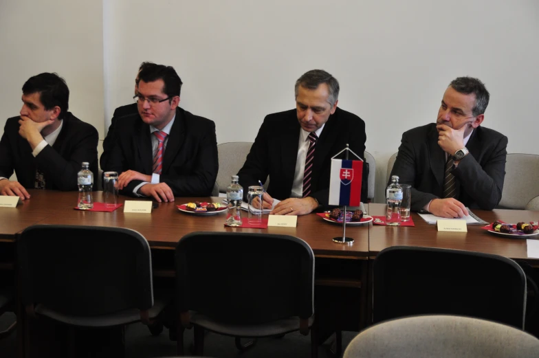 four businessmen are sitting at a wooden table