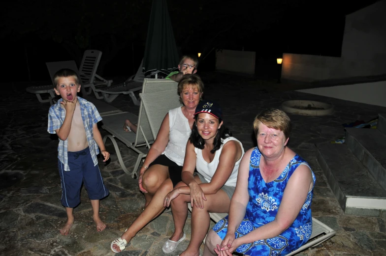 adults and children posing together by a pool at night