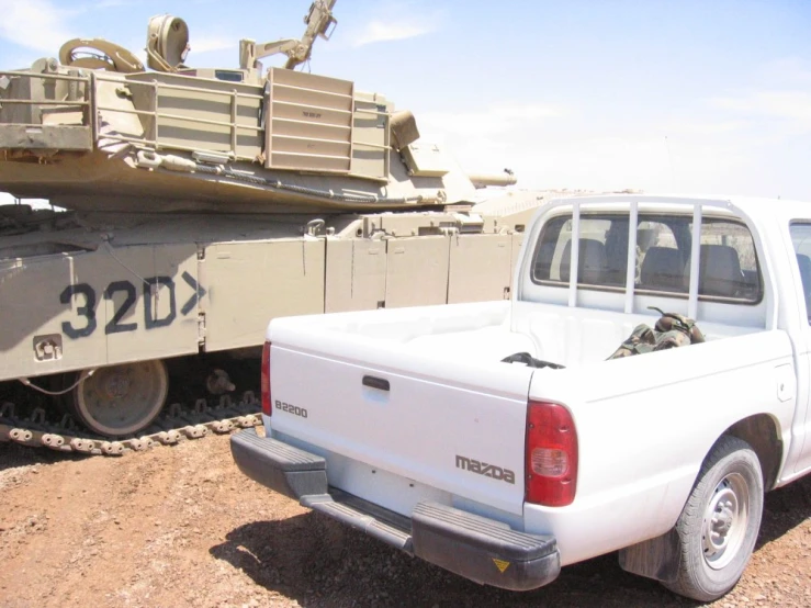 a white truck sits parked beside a tank