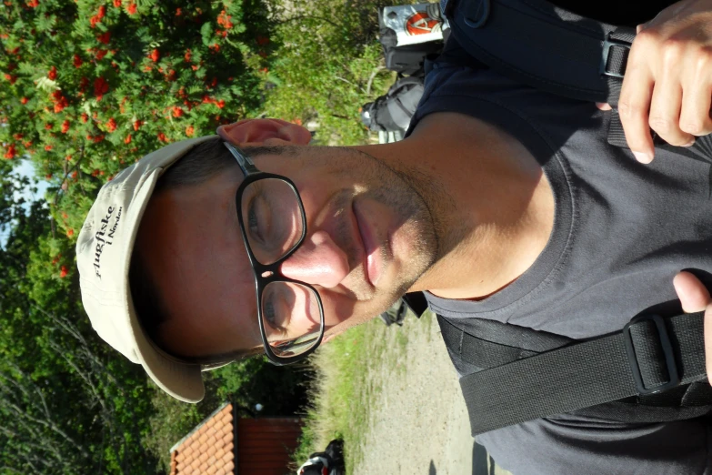 a man wearing glasses and hat while standing outside