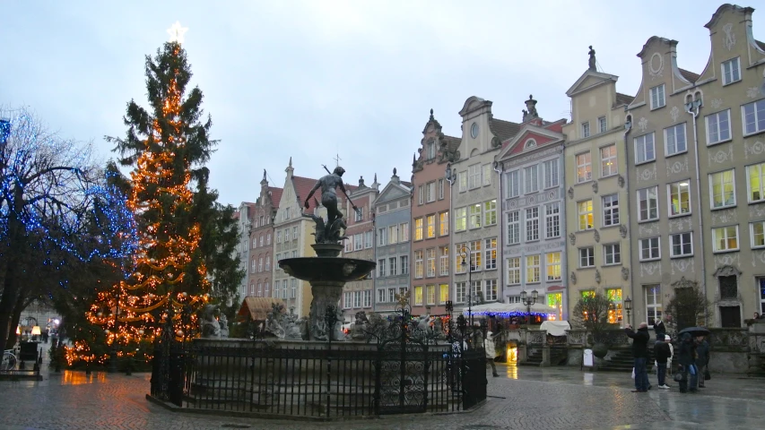 a christmas tree is in a large square with a fountain