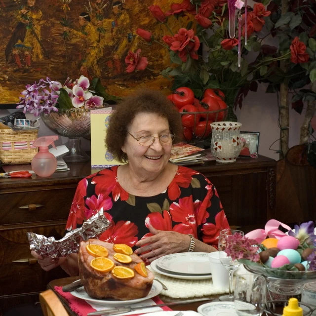 a woman wearing glasses is sitting at a dining table with flowers