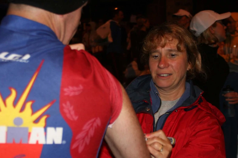 a man with a red and blue shirt standing next to a lady