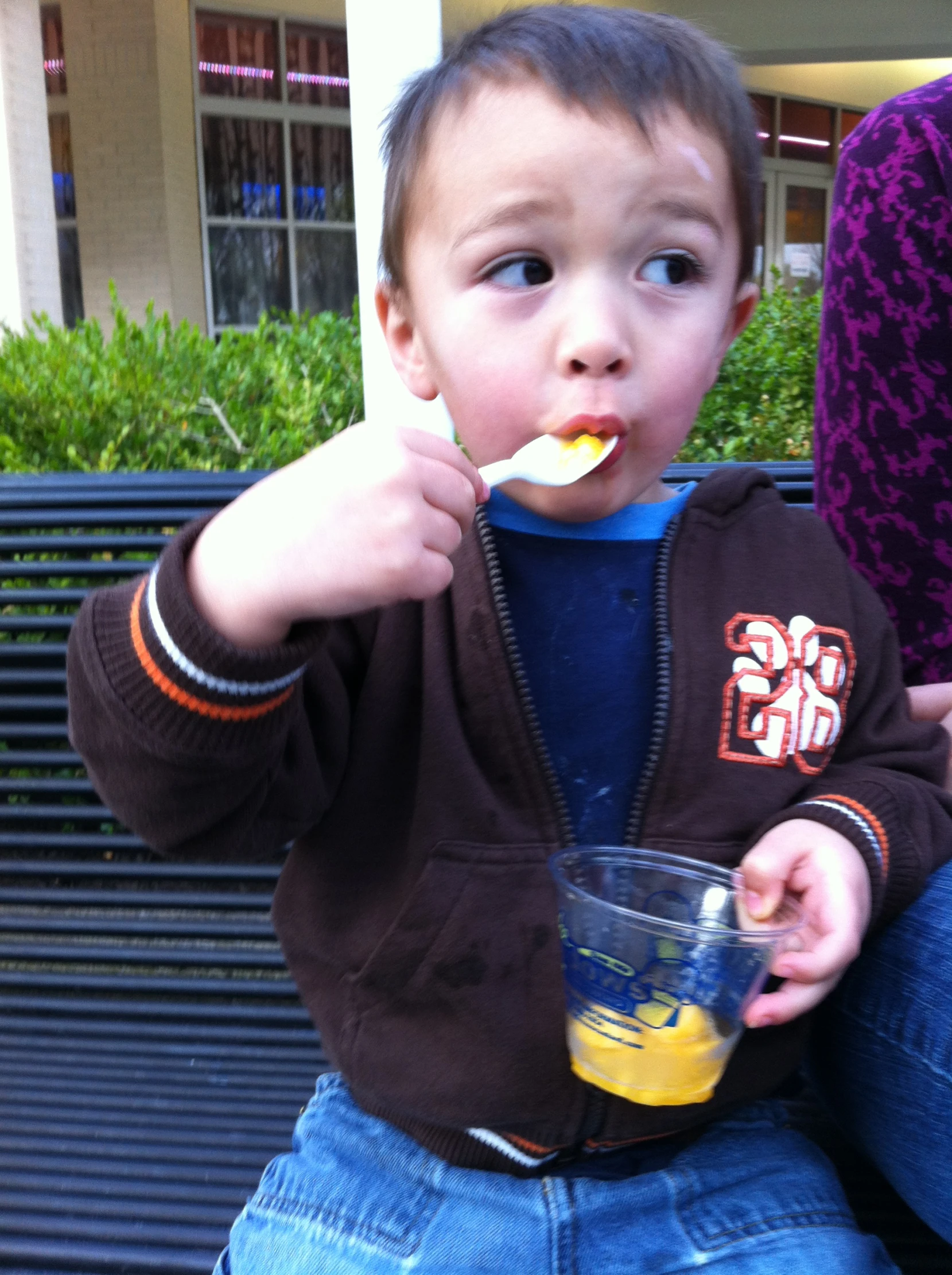 a young child holding an empty cup on his lap