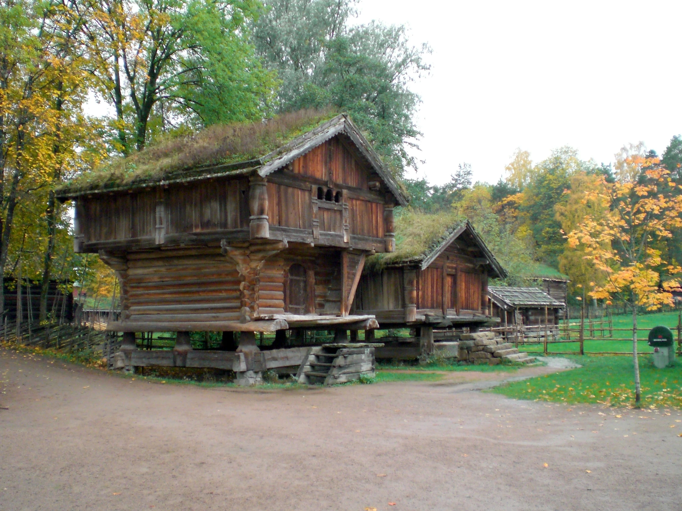 old wooden log buildings are displayed along a path