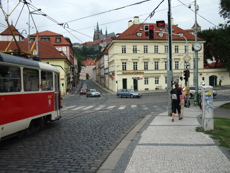 a trolley traveling down a cobblestone road next to tall buildings