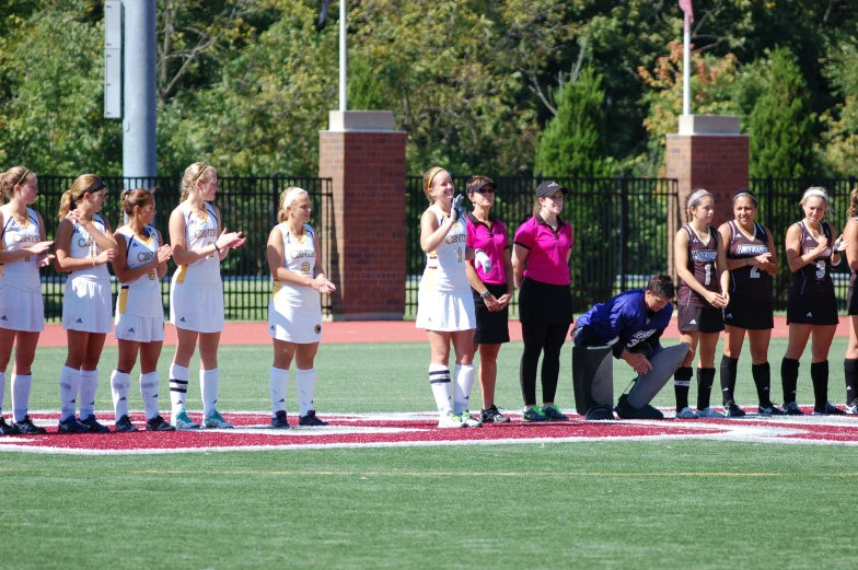 soccer players and coaches lined up on the field