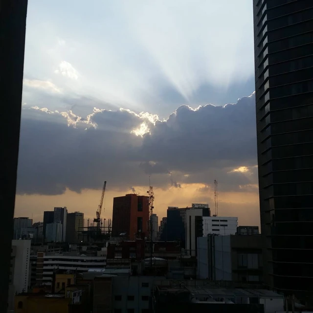 a city skyline with buildings and the sun coming through