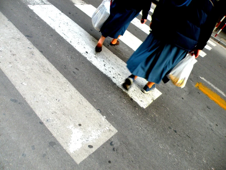 there are people carrying bags crossing the street