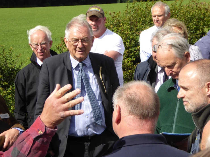 several people looking at an older man in a suit