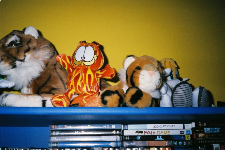 books sit on a shelf beside stuffed animals