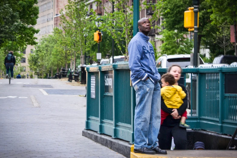 a man stands on the side of a sidewalk by two young children