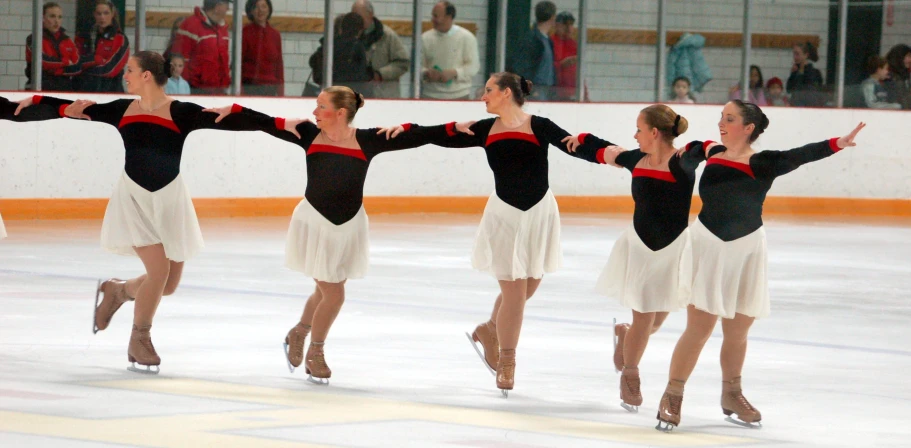 a group of female figure skating on a frozen rink