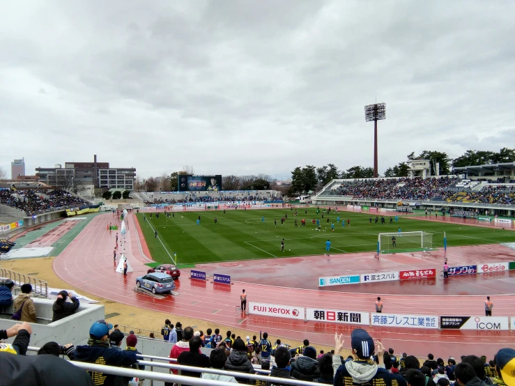 a sports field with cars on it and people looking up at it