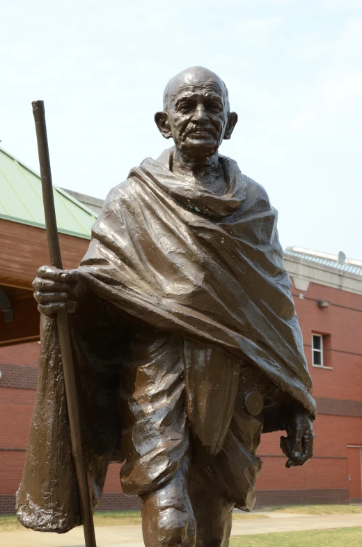 a statue is holding a long stick near a building