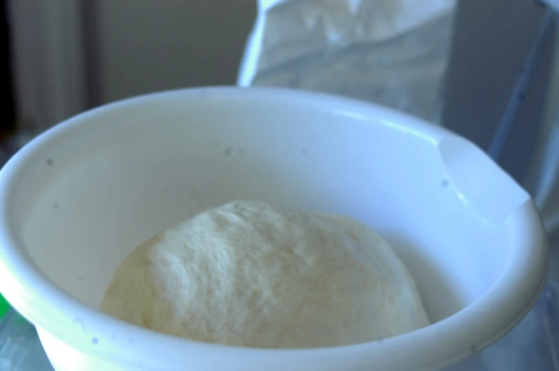 a white bowl filled with raw dough sitting on top of a counter