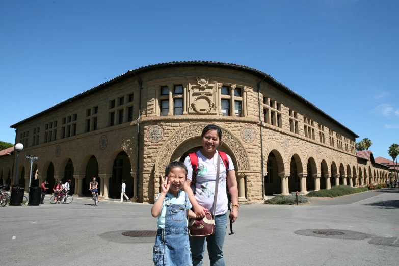 a woman and a girl are standing in front of a building