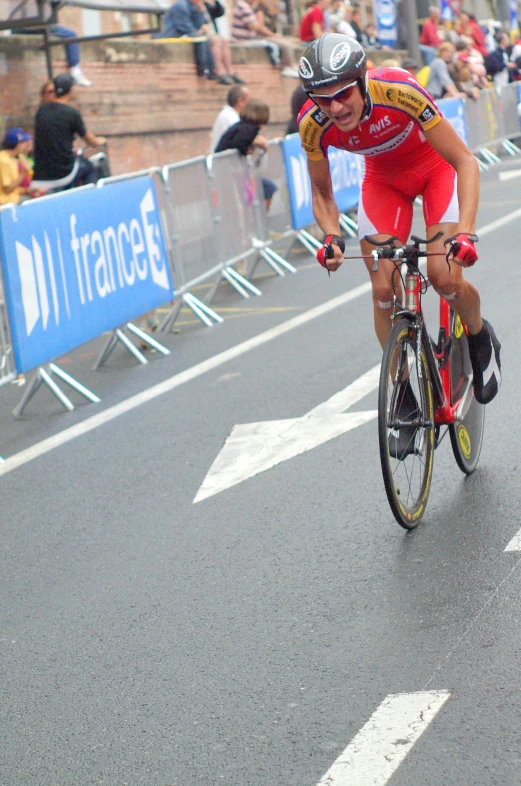 a cyclist going down a street in front of spectators