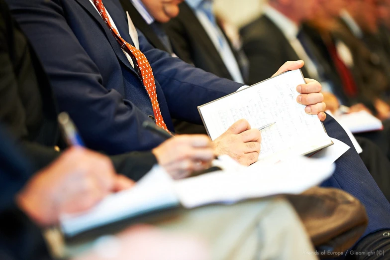 a man's hand is holding an open book in the center of a row of men