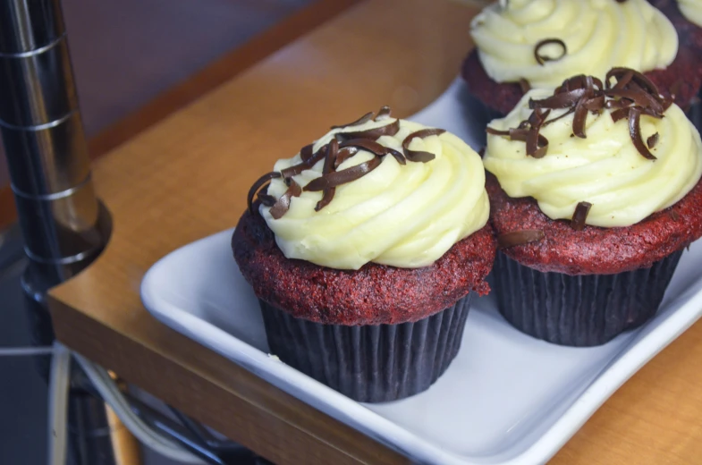 three red velvet muffins sit on a plate