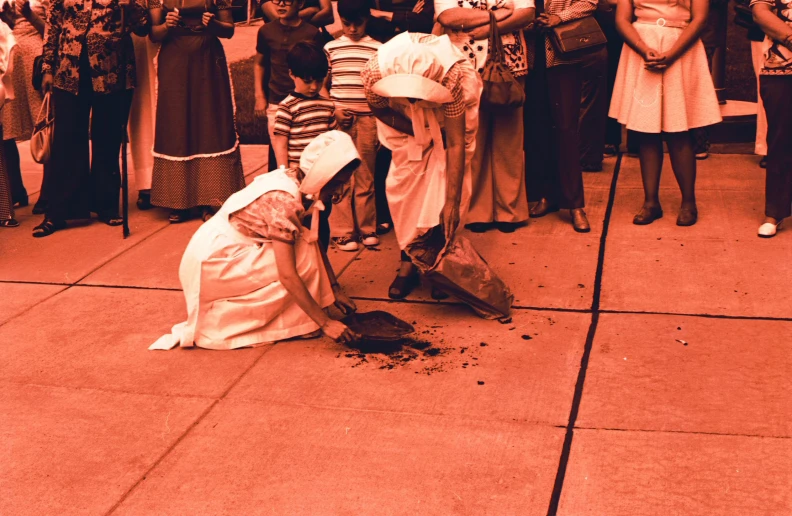 a man digging into dirt as people watch