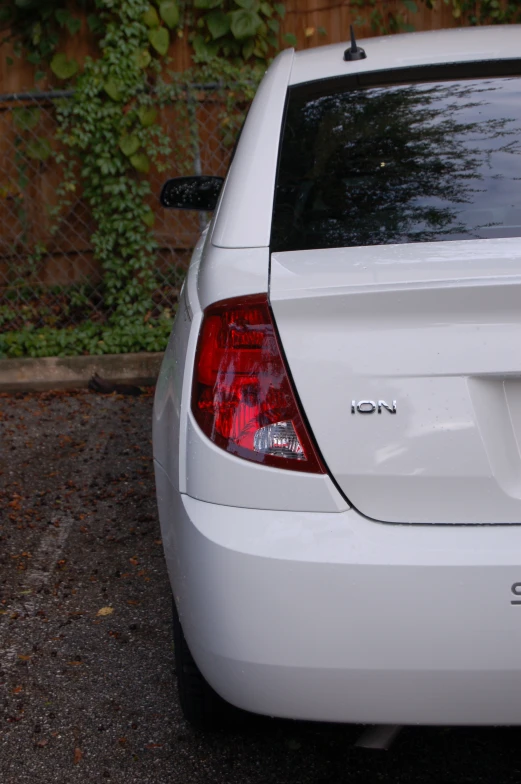 a white car parked in a lot near a fence