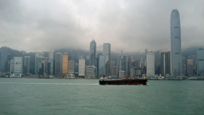 large boat moving down river next to city skyline