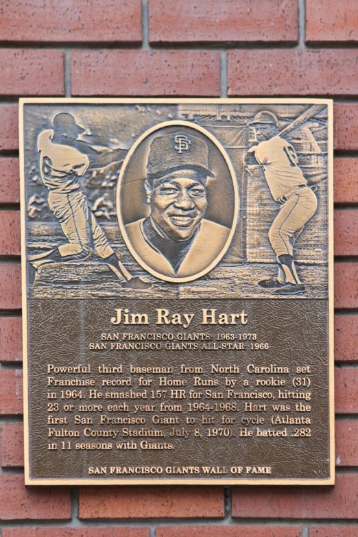 a plaque for a baseball player sits against a brick wall