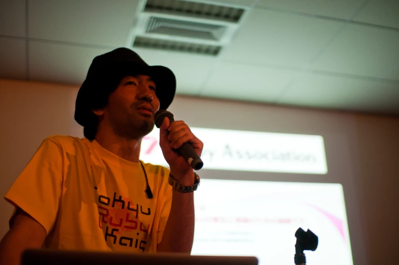 a man wearing a hat is speaking into a microphone