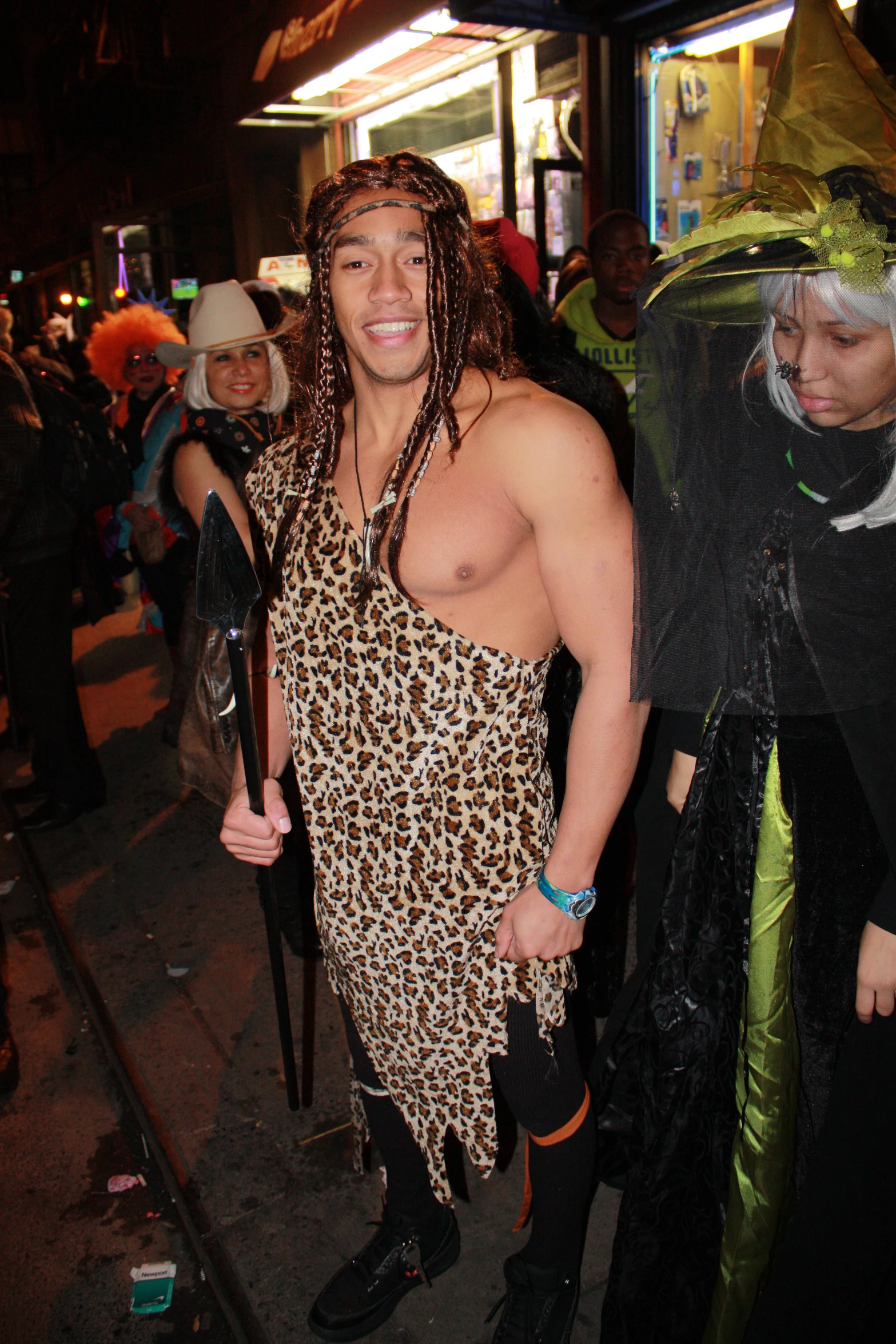 man dressed in a leopard costume is standing with some kind of stick