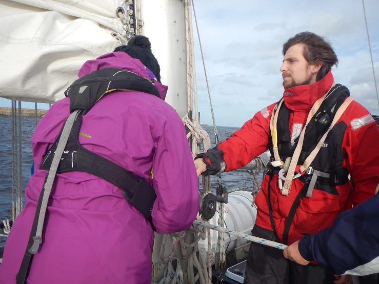 man in bright red coat shaking hands with another person on boat