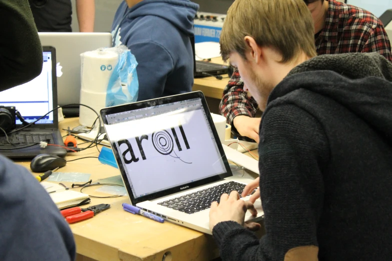 two people are sitting and working on laptops